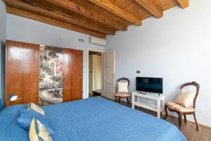 a bedroom with a blue bed and a television at Wondrous Palazzetto 1619 in Magical Burano Island in Burano