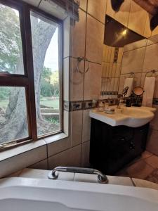 Un baño con bañera, lavabo y ventana. en The Homestay, en Nelspruit
