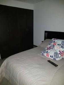 een bed met een kussen en een afstandsbediening bij Apartamento amoblado Central 148 in Bogota