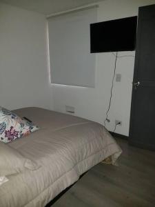 a bedroom with a bed with a television on the wall at Apartamento amoblado Central 148 in Bogotá