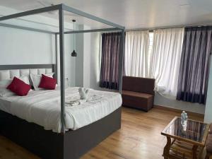 a bedroom with a canopy bed and a chair at Bliss Rooms in Alibaug