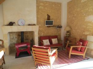 a living room with red chairs and a fireplace at Les jardins de Peychenval in Lamonzie-Montastruc