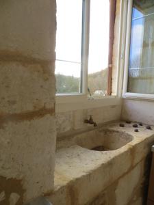 baño con lavabo de piedra y ventana en Les jardins de Peychenval, en Lamonzie-Montastruc