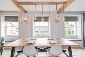 a dining room with a wooden table and white chairs at Oxfordshire Living - The Vanbrugh Apartment - Woodstock in Woodstock