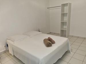 uma cama branca com duas toalhas castanhas em Ô Moulin de la canne à sucre em Mamoudzou