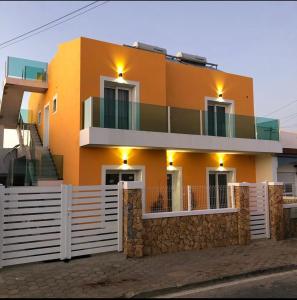 a large orange house with a fence in front of it at ORANGE guest house in Sagres