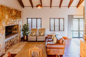 a living room with couches and a stone fireplace at Blue Crane Farm Lodge in Botrivier