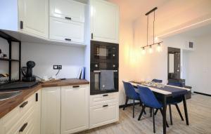 a kitchen with white cabinets and a table with blue chairs at Monos Apartman in Tatabánya