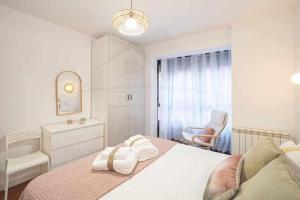 ein weißes Schlafzimmer mit einem Bett und einem Stuhl in der Unterkunft Camino a la Playa in Gijón