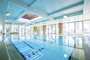 a swimming pool in a building with windows at Village Izukogen in Ito