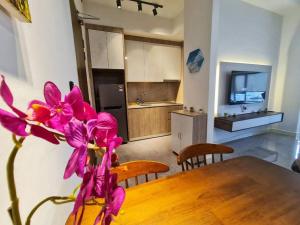 a kitchen with a table and a vase with purple flowers at SeaView#Warmth#Netflix#PrivateBathtub#SeaSideLuxuryCondo#ImperioResidence in Melaka