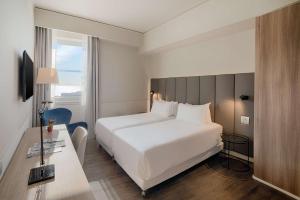 a hotel room with a white bed and a desk at NH Napoli Panorama in Naples