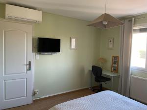 Schlafzimmer mit einem Bett und einem Schreibtisch sowie einem TV an der Wand in der Unterkunft B&B à Toulouse in Balma