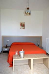 Schlafzimmer mit einem Bett mit einer roten Decke und einem Tisch in der Unterkunft Albergo Diana in Tronzano Lago Maggiore