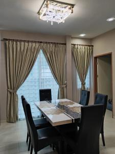 a dining room table with black chairs and a chandelier at Ann_HomeStay in Sandakan