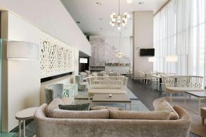 - un salon avec un canapé, des tables et des chaises dans l'établissement NH Parma, à Parme