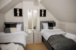 two beds in a bedroom with white and black at Tower Square House in Alloa