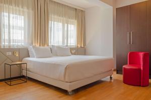 a bedroom with a large white bed and a red chair at NH Collection Roma Giustiniano in Rome