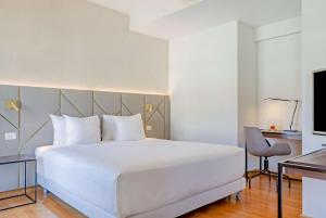 a bedroom with a large white bed and a desk at NH Collection Roma Giustiniano in Rome