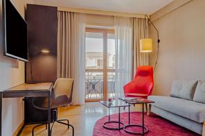 ローマにあるNH ジュスティニアーノ ホテルのリビングルーム(ソファ、赤い椅子付)