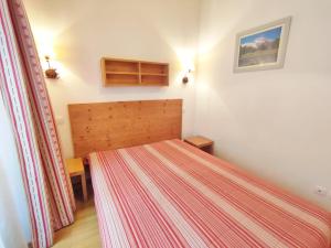 une petite chambre avec un lit avec un couvre-lit rayé dans l'établissement Ostal, T3, centre Luchon, wifi, casier à skis, ascenseur, 6 personnes, à Luchon