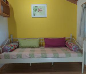 a couch with colorful pillows on a yellow wall at Beim Grafen in Frasdorf