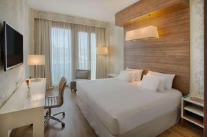 um quarto de hotel com uma cama grande e uma secretária em NH Collection Milano President em Milão