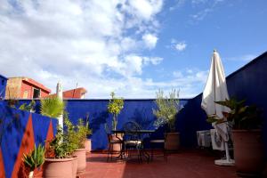 a patio with a table and umbrella and potted plants at Riad Dar La Rose in Marrakech