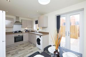 uma cozinha com armários brancos e uma mesa com cadeiras em Urban Bliss, Park with Ease 3 Bed New Build Home em Leicester