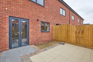a brick building with a wooden fence in front of it at Urban Bliss, Park with Ease 3 Bed New Build Home in Leicester