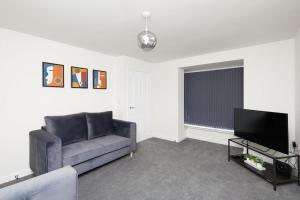 uma sala de estar com um sofá e uma televisão de ecrã plano em Urban Bliss, Park with Ease 3 Bed New Build Home em Leicester