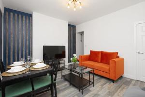 a living room with an orange couch and a table at Sleek & Stylish Modern 4-Bedroom Urban Retreat in Leicester