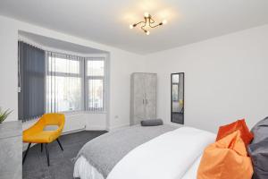 a white bedroom with a bed and a yellow chair at Sleek & Stylish Modern 4-Bedroom Urban Retreat in Leicester