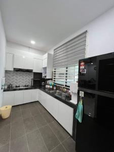 cocina con armarios blancos y nevera negra en Homestay Kemaman Fyna06, en Kampong Kemaman