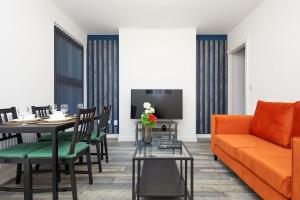 a living room with an orange couch and a table at Sleek & Stylish Modern 4-Bedroom Urban Retreat in Leicester