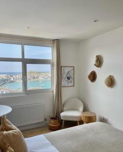 1 dormitorio con ventana, 1 cama y 1 silla en Harbour View House en St Ives