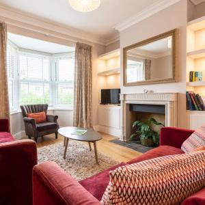 a living room with red furniture and a fireplace at Norfolk House - Stamford in Stamford