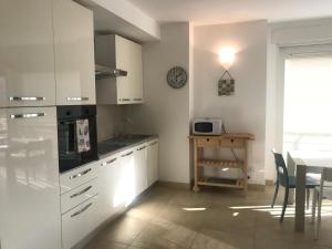 a kitchen with white cabinets and a table and a window at Appartamento Rosa Residenza Prealba in Levanto