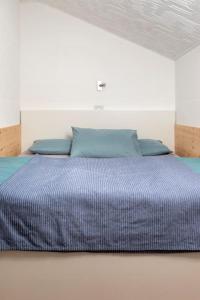 Cama en habitación blanca con edredón azul en Hike Bike & more Ferienappartement by Alex, en Rablà