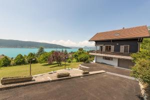 a house with a parking lot next to a lake at La Villa des Grillons, outstanding lake view and private garden - LLA Selections by Location Lac Annecy in Veyrier-du-Lac