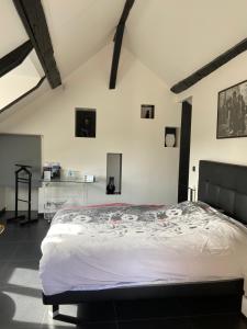 ein großes Bett in einem Zimmer mit weißen Wänden in der Unterkunft Les Crinieres En Brie in Saint-Ouen-en-Brie