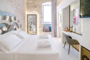 Biała sypialnia z dużym łóżkiem i biurkiem w obiekcie Palazzo Vico Bianco Raro Villas Homes Collection w mieście Ostuni