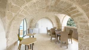 una sala da pranzo con arco in pietra, tavoli e sedie di Palazzo Vico Bianco Raro Villas Homes Collection a Ostuni