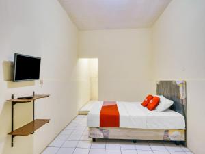 ein Schlafzimmer mit einem Bett und einem TV an der Wand in der Unterkunft SUPER OYO 591 Mn Residence Syariah in Jakarta