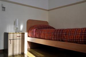 a bedroom with a bed with a plaid blanket on it at Ostello Cuneo in Cuneo