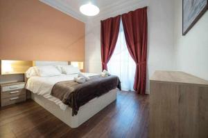 een slaapkamer met een bed en een raam met rode gordijnen bij Lavaderu Apartamento in Gijón