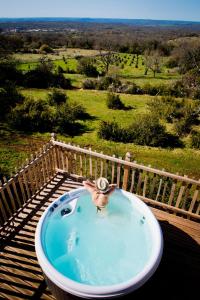 Ein Mann in einer Whirlpool-Badewanne auf einer Terrasse in der Unterkunft Cabane Spa La Truffière - Cantecor in Alvignac