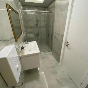 a white bathroom with a shower and a sink at Hasanbey Apart Otel in Belek