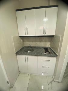 a small kitchen with a sink and white cabinets at Hasanbey Apart Otel in Belek