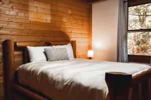 Cama en habitación con pared de madera en Wolf Creek Cabin at 36 North - Hot Tub, en Purlear